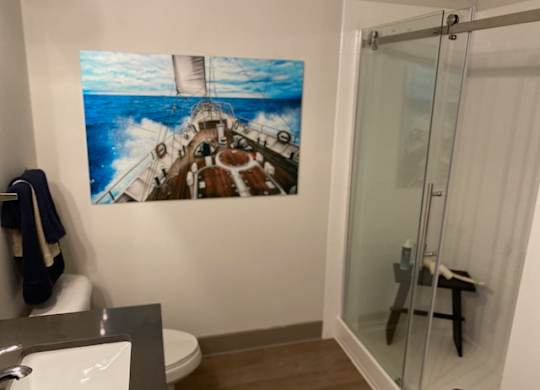 A bathroom with a large picture of a ship on the wall.
