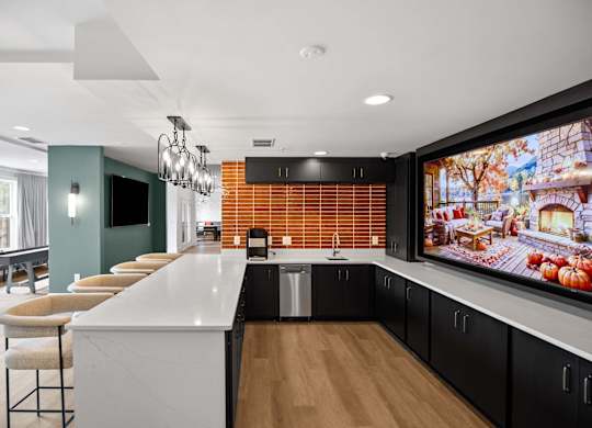 A modern kitchen with a long white island and a large TV mounted on the wall.