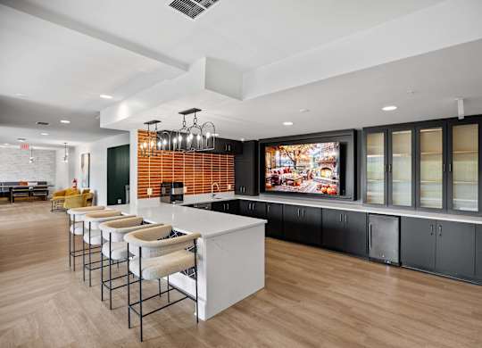 A modern kitchen with a long bar and stools.