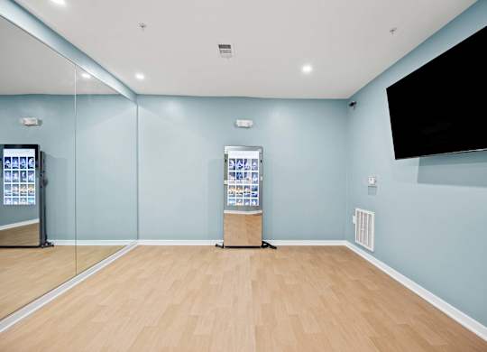 A room with a wooden floor and a wall-mounted television.