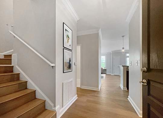 A hallway with a staircase and a doorway leading to another room.
