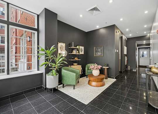 A black and white hallway with a green chair and a plant.