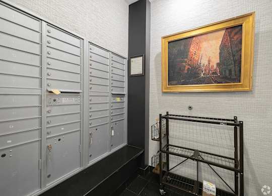 A row of mailboxes are lined up against a wall with a painting hanging above them.