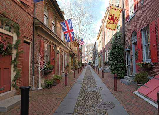 A cobblestone street with a flag on the left and a flag on the right.