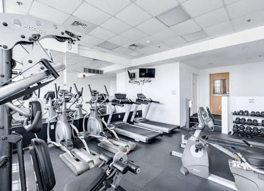 A gym with a variety of equipment including treadmills, weights, and exercise machines.