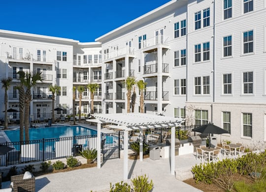 A white apartment building with a pool in the courtyard.