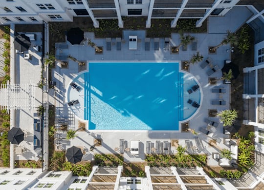 A swimming pool surrounded by lounge chairs and umbrellas.