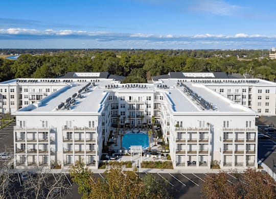 A large white hotel with a pool in the middle of it.