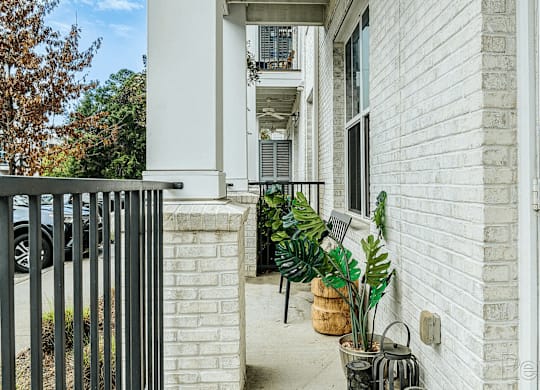 A white house with a black gate and plants on the porch.