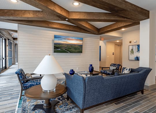A living room with a blue couch and a painting on the wall.