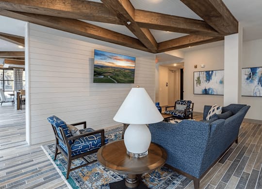 A living room with a blue couch, a wooden table, and a painting on the wall.