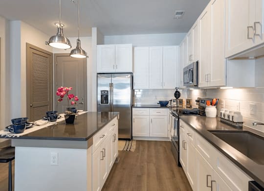 A kitchen with white cabinets and a black countertop.