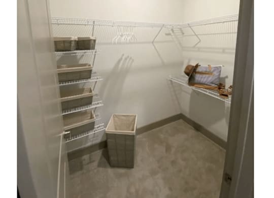 A small, empty walk-in freezer with a single shelf and a plastic bin on the floor.