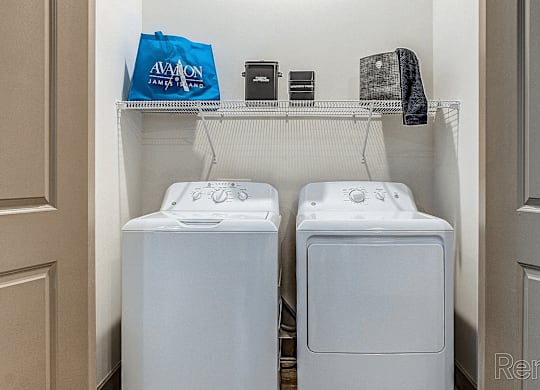 Two white washing machines in a small laundry room.