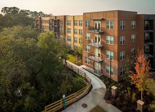 A view of apartment buildings with a walkway and trees in the foreground.