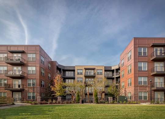 A large apartment complex with multiple balconies and trees in the front yard.