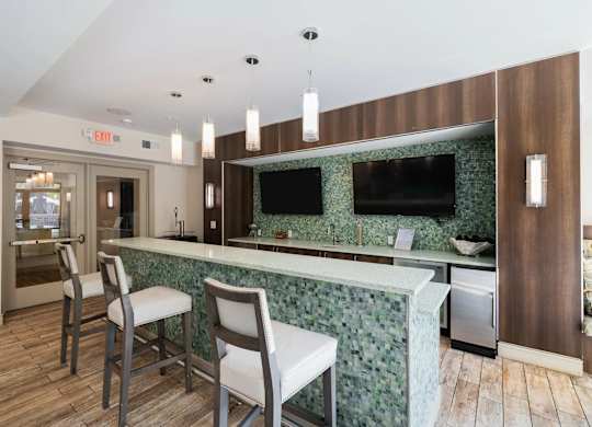 A kitchen with a green backsplash and a bar area with two chairs.