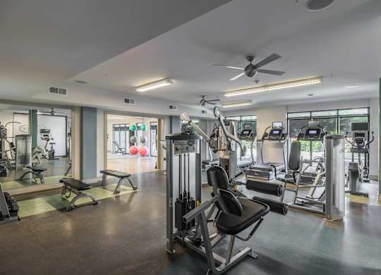 A gym with a variety of equipment including treadmills, weights, and exercise machines.