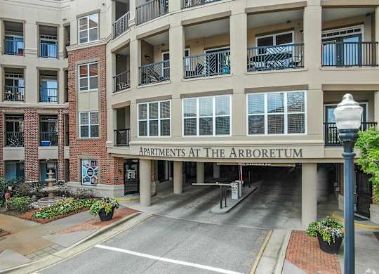 The Arboretum Apartments building has a brick facade and is surrounded by greenery.