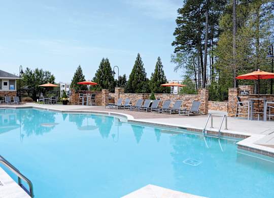 A large swimming pool with a metal ladder and a small building in the background.