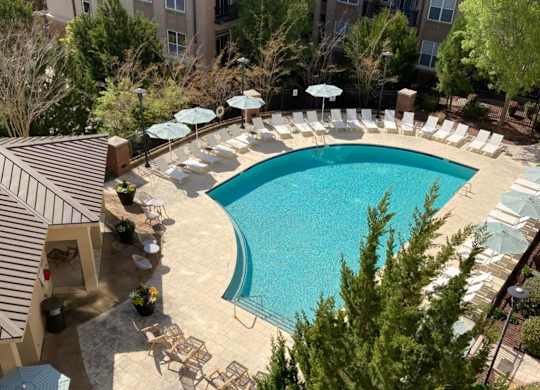 A large swimming pool surrounded by chairs and umbrellas.