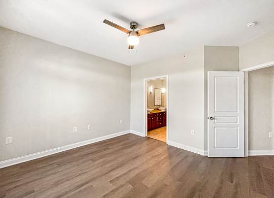 A room with a ceiling fan and wooden flooring.