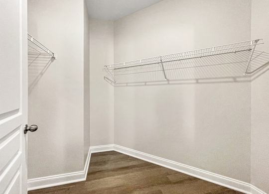 A white closet with a door and shelves.