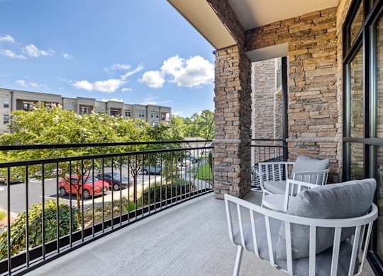A balcony with a grey sofa and a stone pillar.