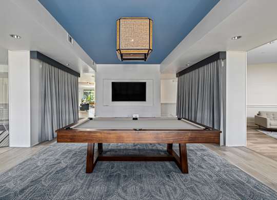A billiard table is in the middle of a room with a television.