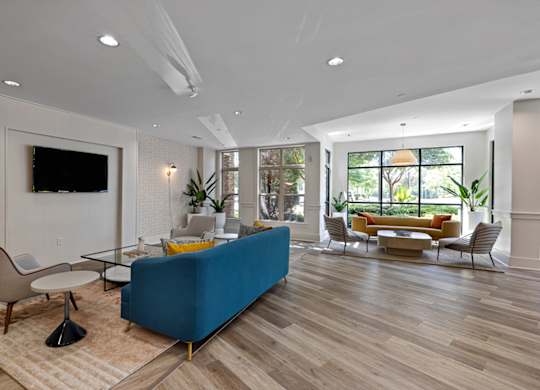 A blue couch sits in a spacious living room with a television mounted on the wall.