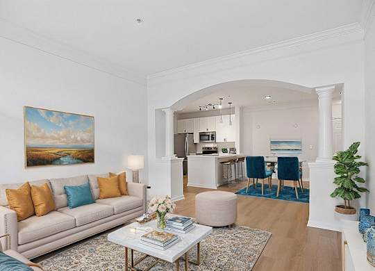 A living room with a beige couch, a coffee table, and a painting on the wall.