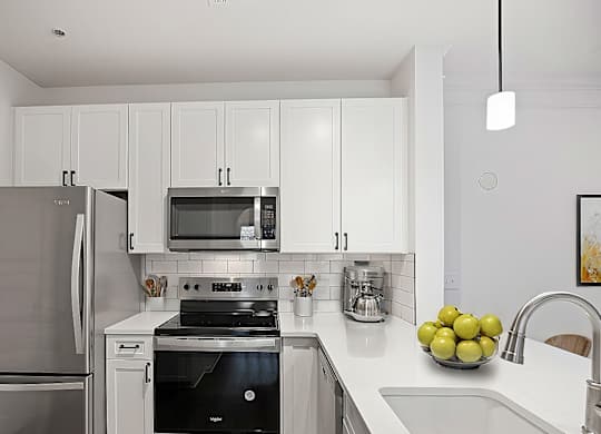 A modern kitchen with a stainless steel refrigerator and a black stove top oven.