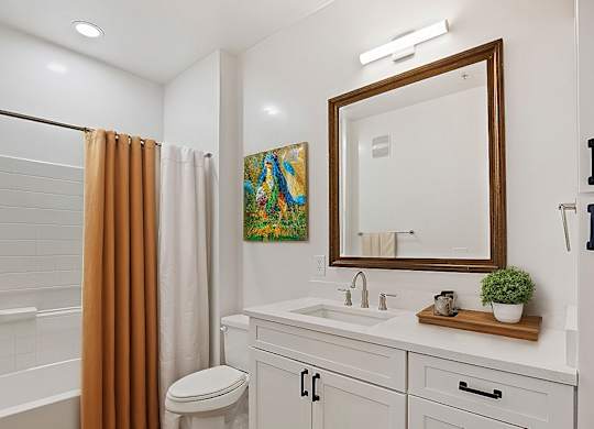 A bathroom with a white toilet, sink, and a brown shower curtain.