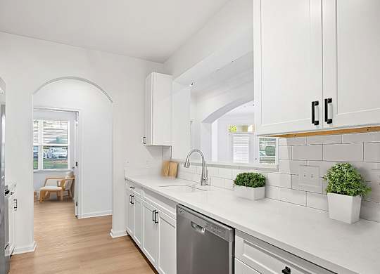 A modern kitchen with white cabinets and a stainless steel dishwasher.