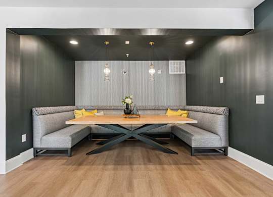 A modern dining area with a grey sofa and a wooden table.