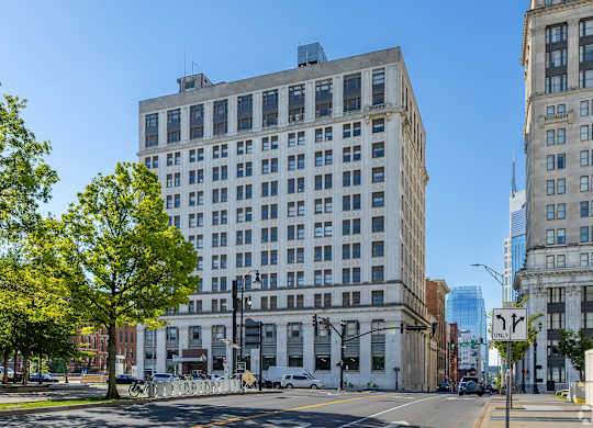A street view of a city with a large white building in the middle.