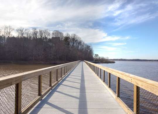 A wooden boardwalk extends into the distance over a body of water.