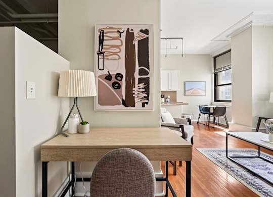 A modern home office with a desk, chair, and a large abstract painting on the wall.