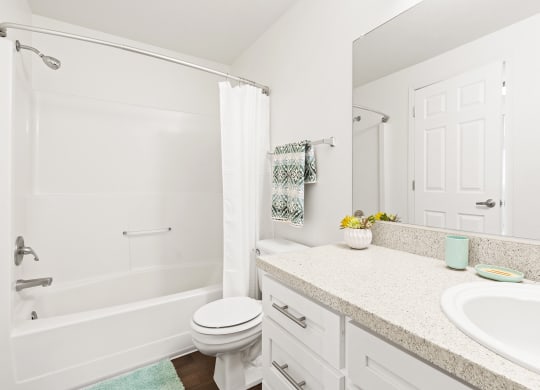 White bathroom with new white cabinets, large mirror, white toilet and full size bathtub.at North Pointe, Post Falls, 83854
