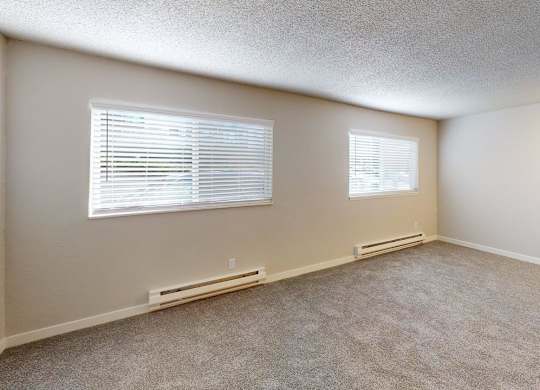 Bright one-bedroom layout at Peak 88 Apartments Renton with two windows allowing natural light and plush carpeting.
