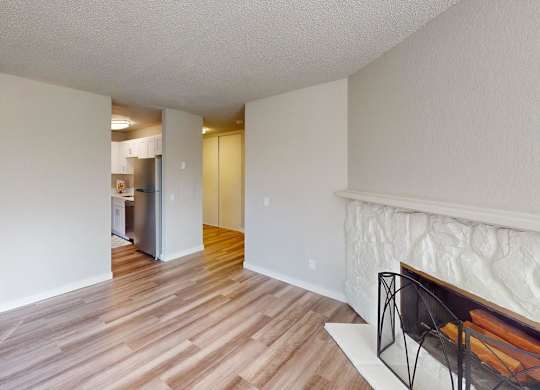 Open-concept living space at Peak 88 Apartments Renton featuring wood-style flooring, fireplace, and sliding doors to balcony.