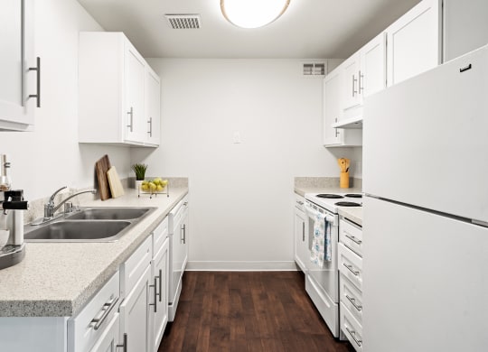A galley-style kitchen with white cabinets and appliances and new countertops.at North Pointe, Post Falls Idaho