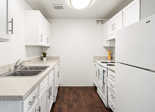 Bright white kitchen with dark faux wood flooring, new cabinets and countertops.at North Pointe, Post Falls, ID