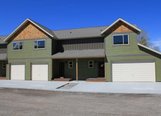 the front of a green house with two garage doors at Copper Pines, Bozeman, MT