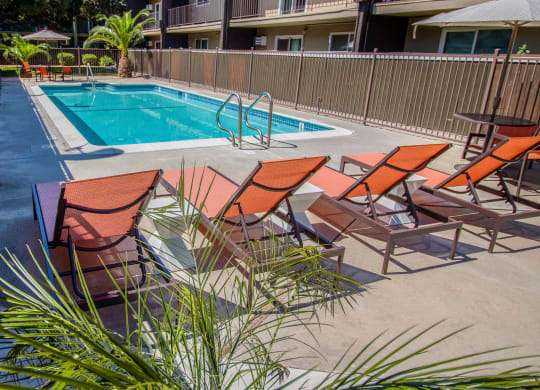 a pool with a poolside deck with chairs and a swimming pool at Ella 1711 Apartments, Woodland, CA