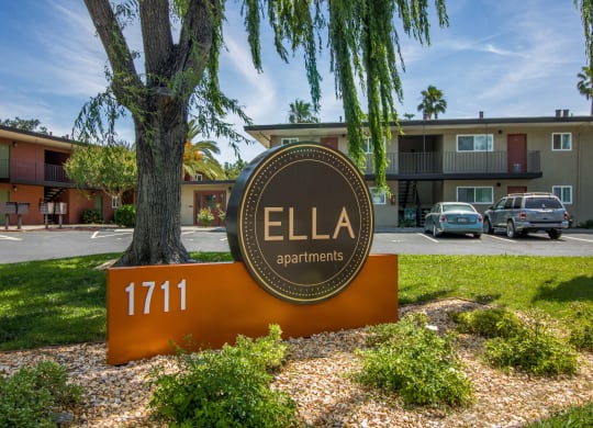 a sign that says apartments in front of a tree at Ella 1711 Apartments, Woodland, CA 95695