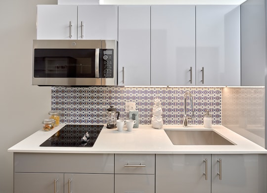 a kitchen with white cabinets and a sink and a microwave at Enve, Seattle Washington