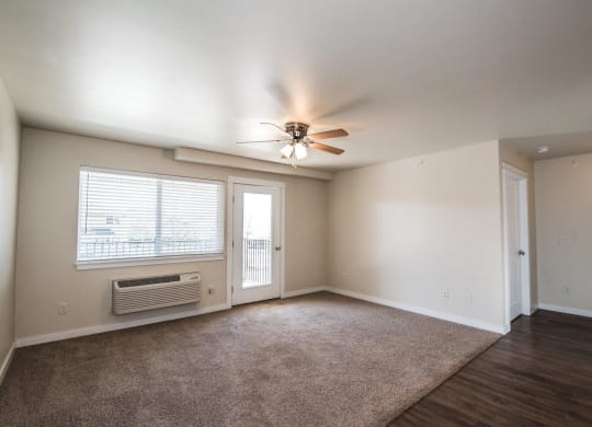 an empty living room with a ceiling fan and a window