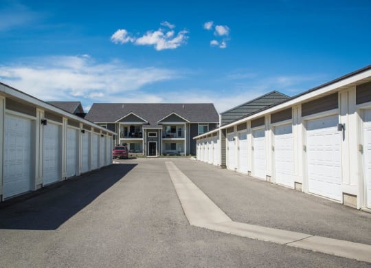 a row of garages with white doors and a house in the background at Madison Park, Bozeman, MT, 59718