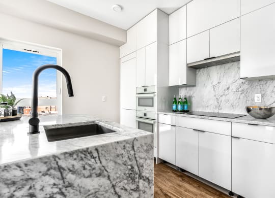 a kitchen with white cabinets and marble counter tops and a sink  at Oslo, Seattle, 98102